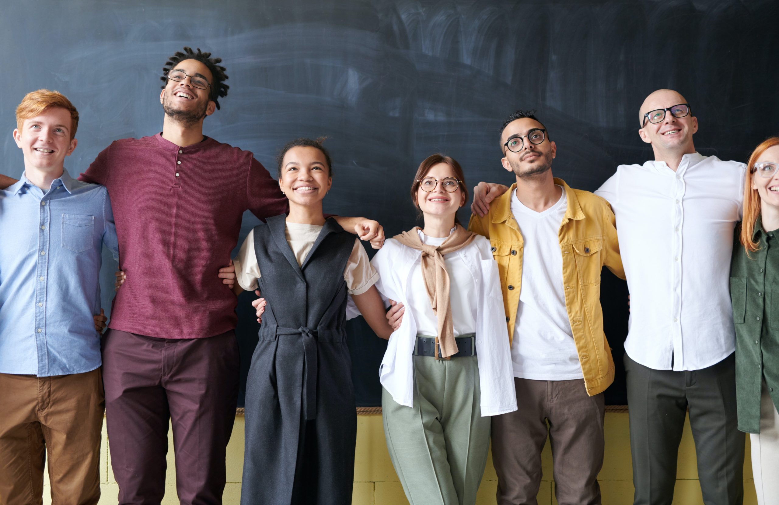 Team of smiling employees arms connected.