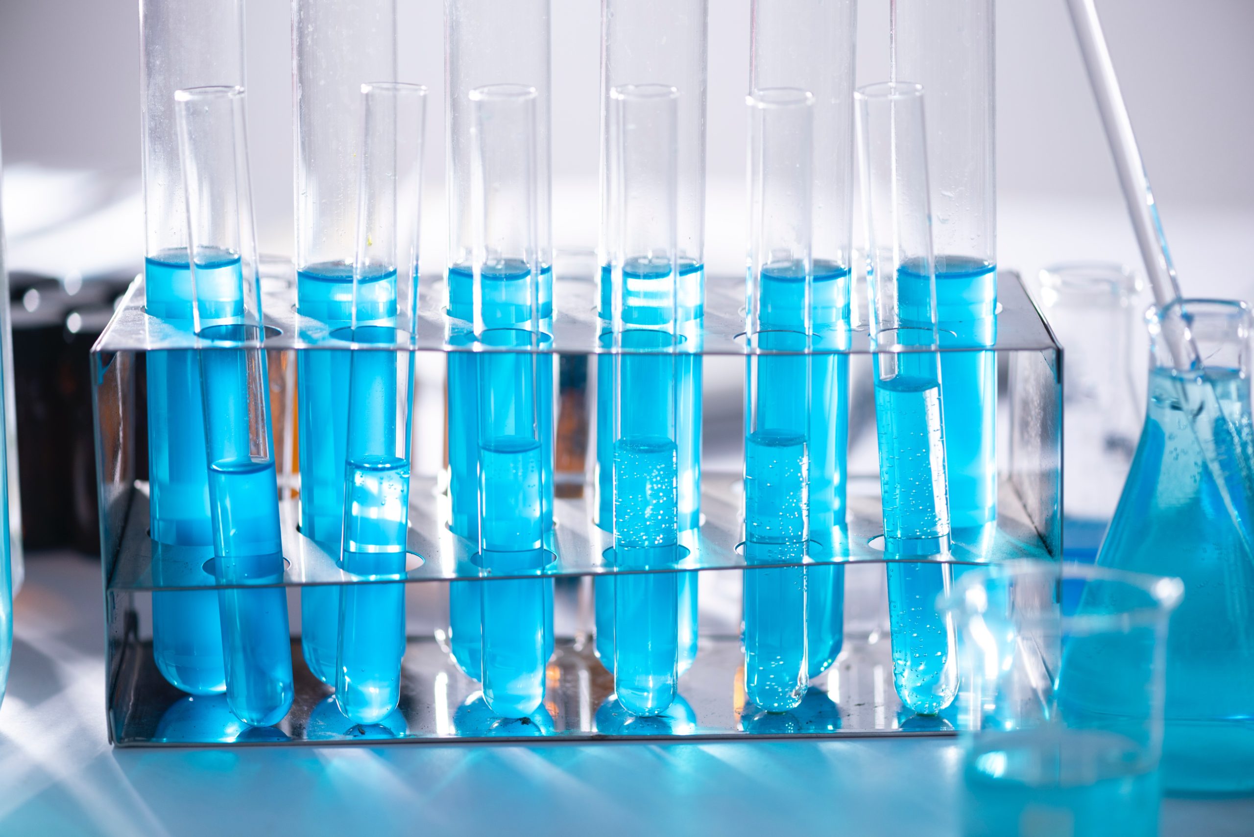 A row of test beakers containing blue liquid