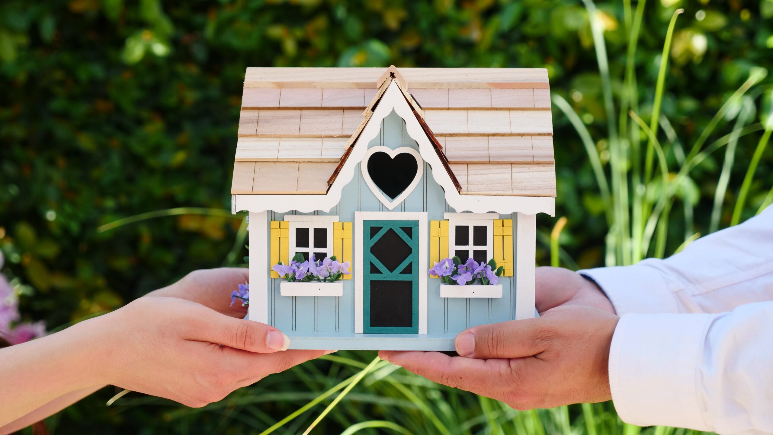 Couple holding a house model in their hands.